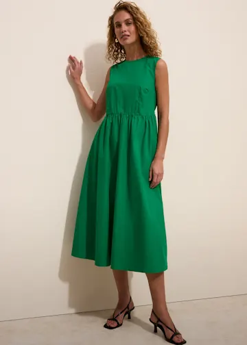 Grünes Midikleid mit geschnürten schwarzen Sandalen.