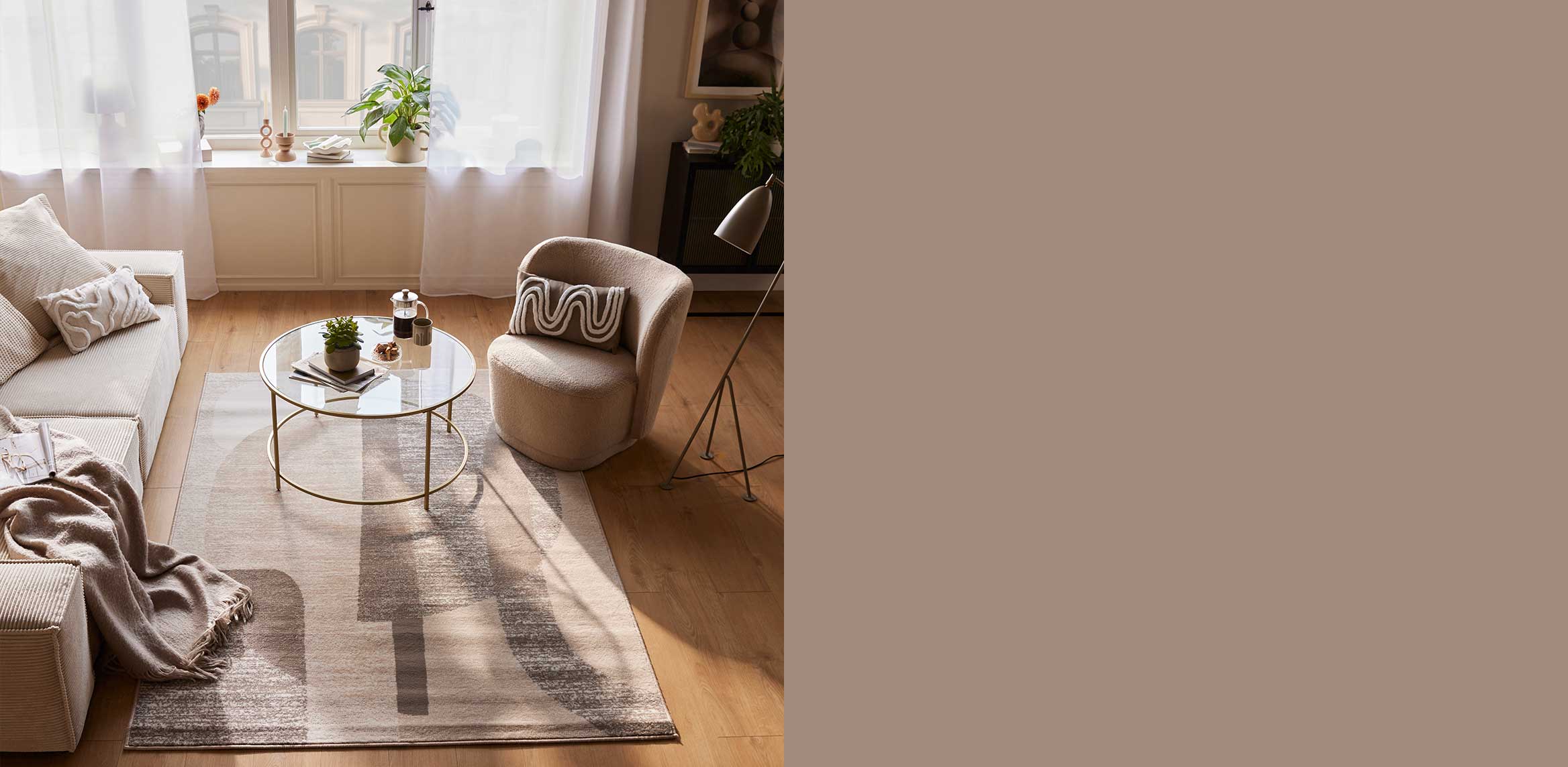 Gemütliches Wohnzimmer mit beigem Sessel, flauschiger Decke und stilvollem Teppich in warmen Erdtönen.