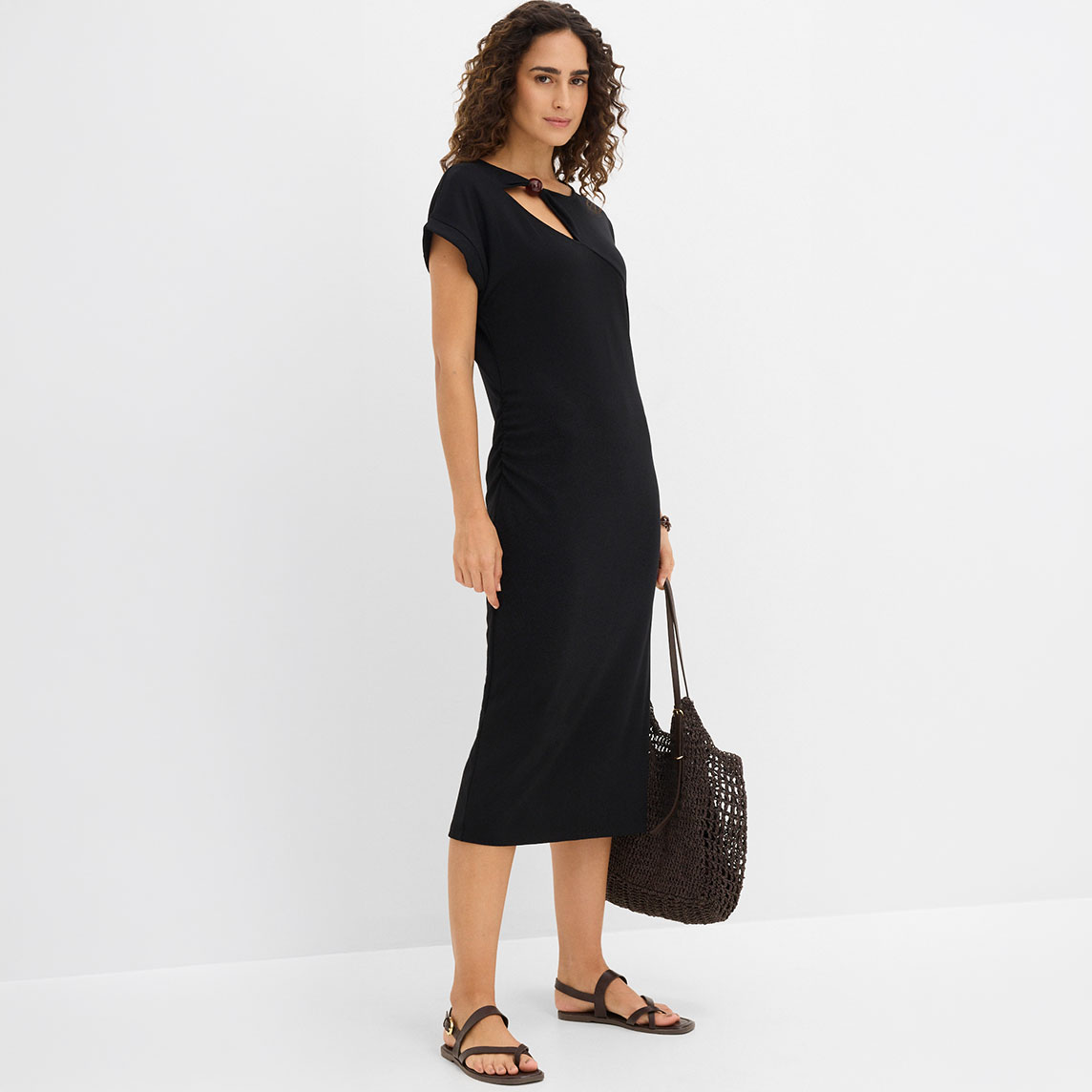 Elegantes schwarzes Midi-Kleid mit asymmetrischem Ausschnitt und passender schwarzer Handtasche.