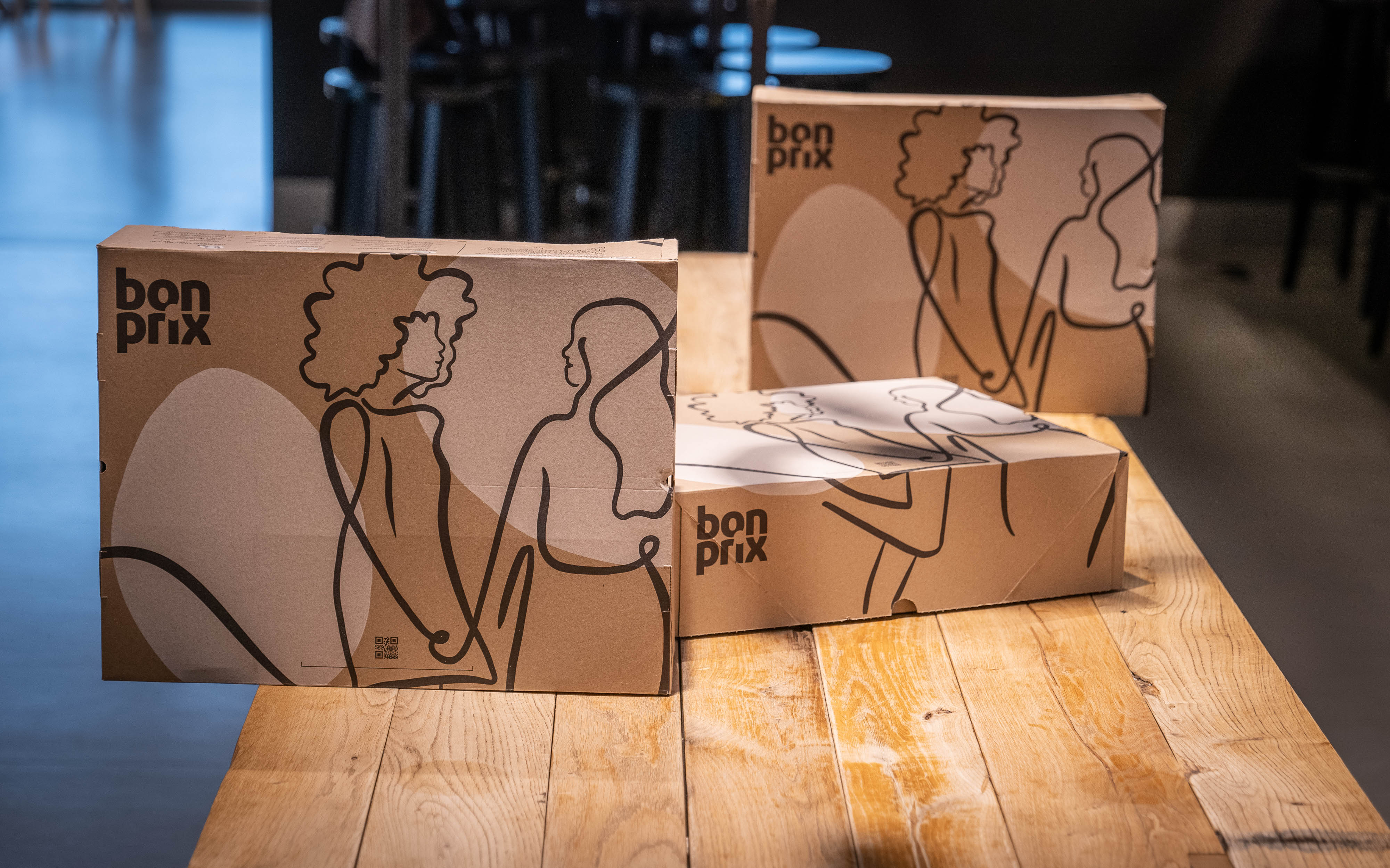 Braune Kartons mit minimalistischen Zeichnungen zeigen moderne, stilvolle Kleidung für den urbanen Alltag.