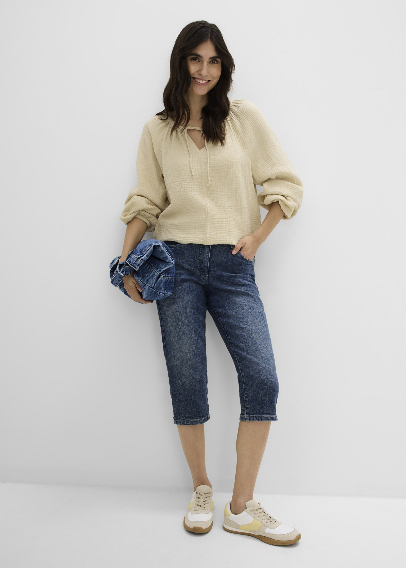 Helle Bluse, verwaschene 3/4-Jeans und bequeme Sneaker. 