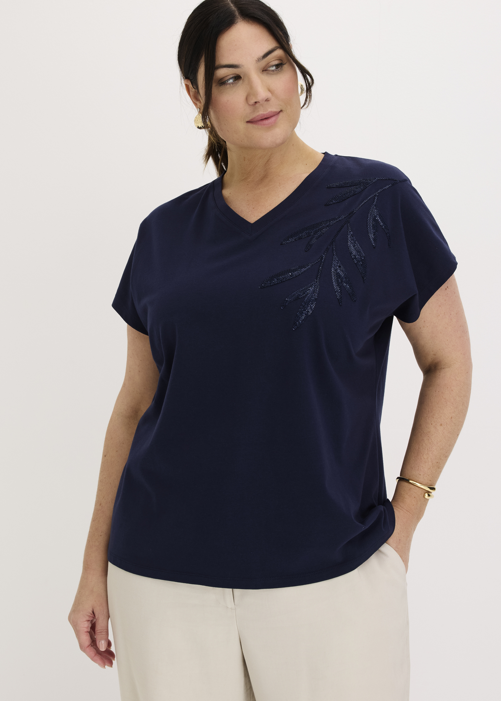 Stilvolles marineblaues V-Shirt mit Blätterapplikation, dazu helle Hose und Armreif.