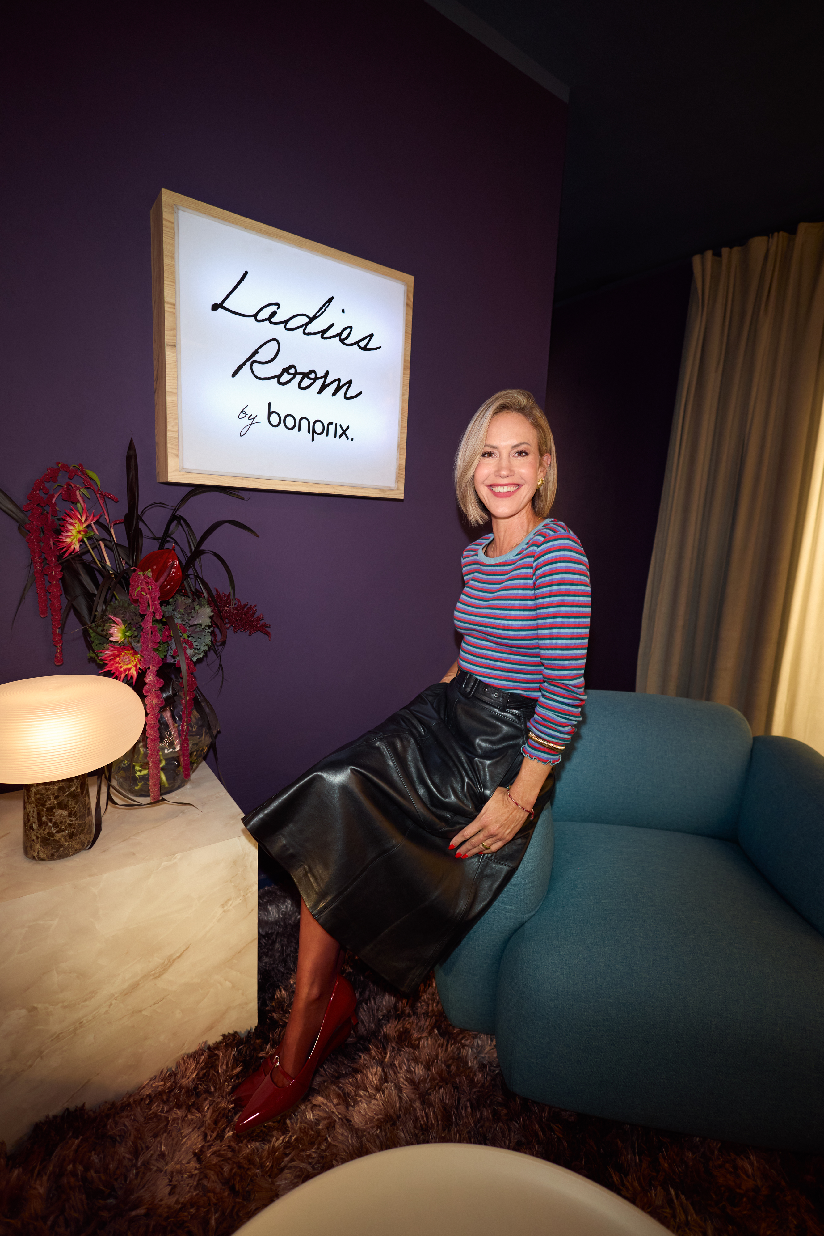 Elegantes auberginefarbenes Kleid, schwarze Strumpfhose, hohe Stiefel und passende Jacke.