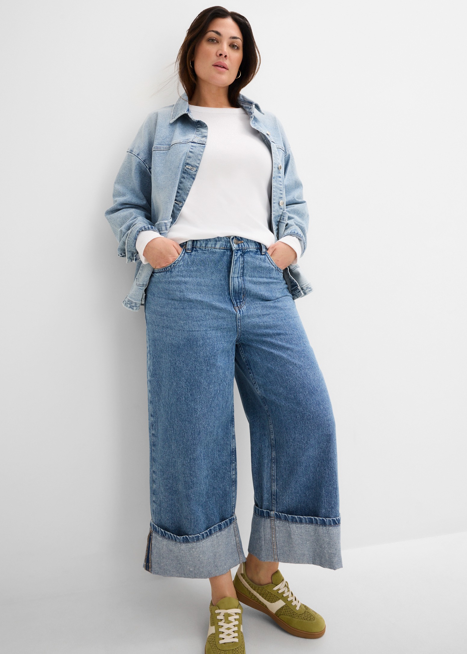 Jeansjacke, weite Jeans mit Umschlag, weißes Shirt und grüne Sneaker.