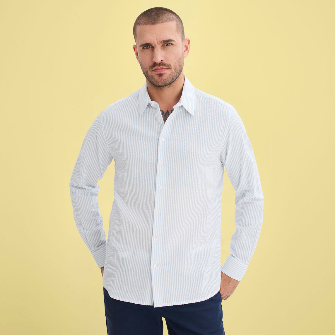 Mann trägt ein klassisches weißes Hemd mit feinen Streifen und dunkle Hose.