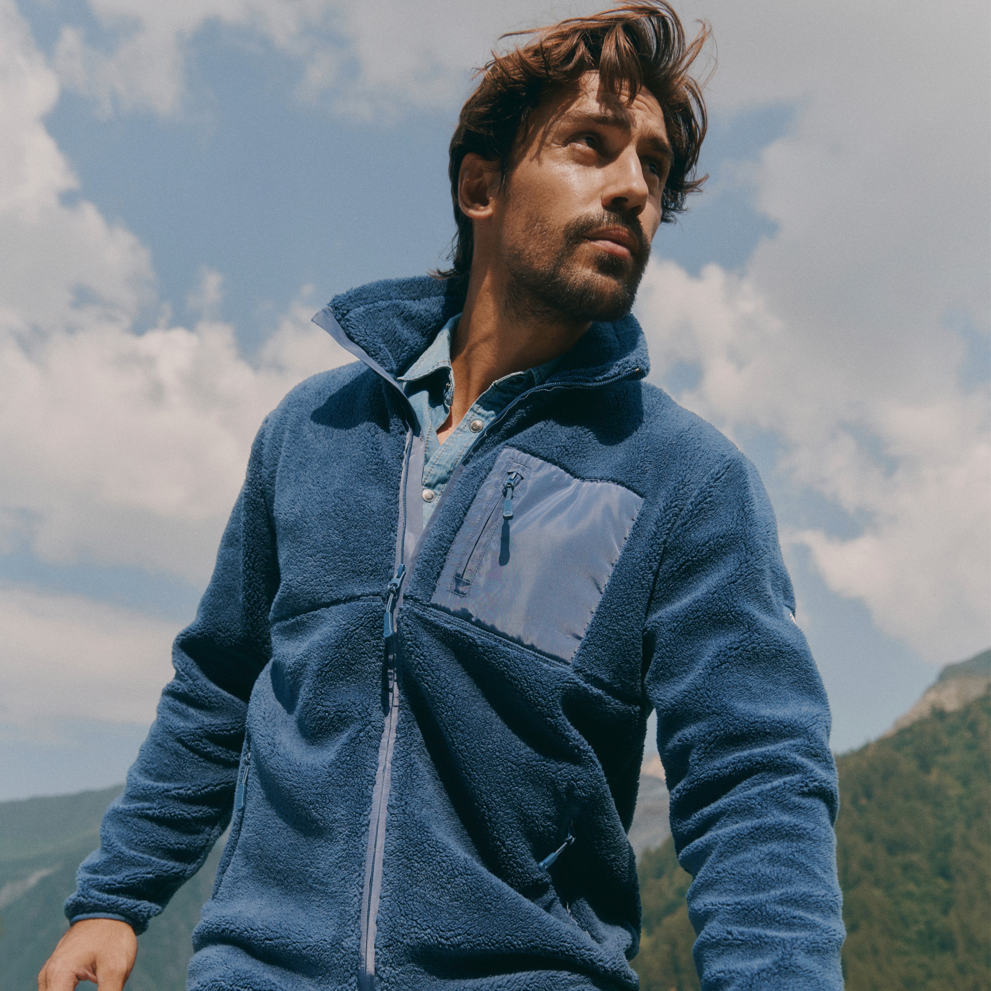 Der Mann trägt eine gemütliche blaue Fleecejacke und dazu passende blaue Hose.