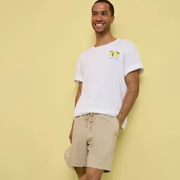Lässiges Outfit mit weißem T-Shirt, beigefarbenen Shorts und weißen Sneakern.