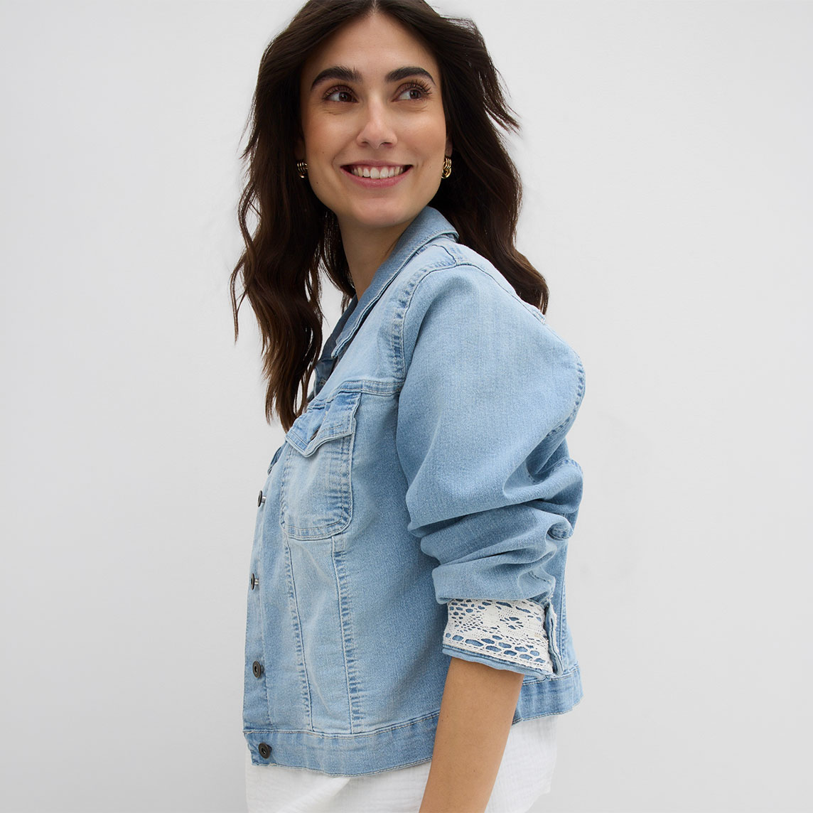 Helle Jeansjacke mit umgekrempelten Ärmeln und weißem Spitzendetail am Handgelenk.