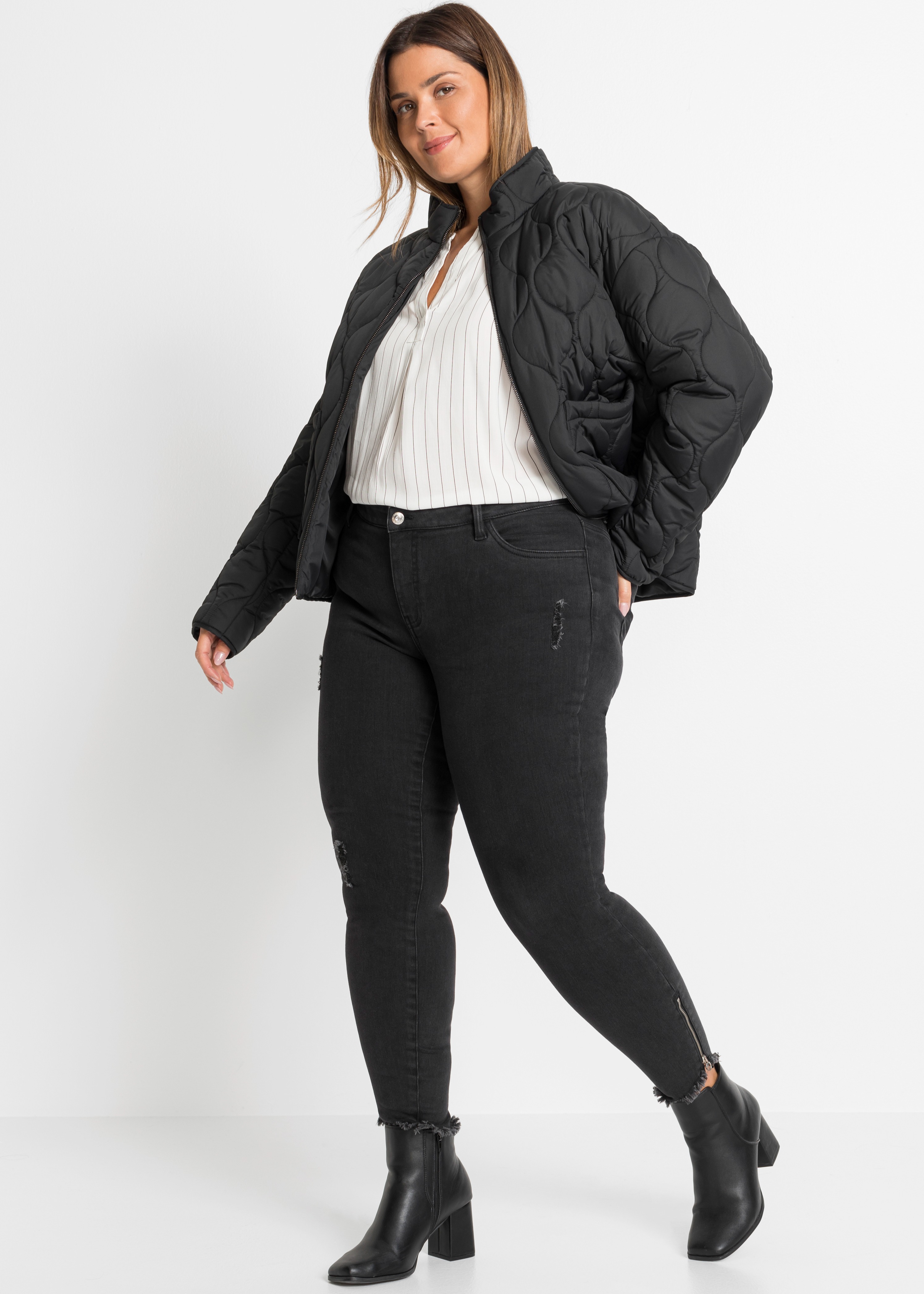 Schwarze Steppjacke, gestreifte Bluse, Jeans mit Reißverschlüssen und lässige Stiefeletten.