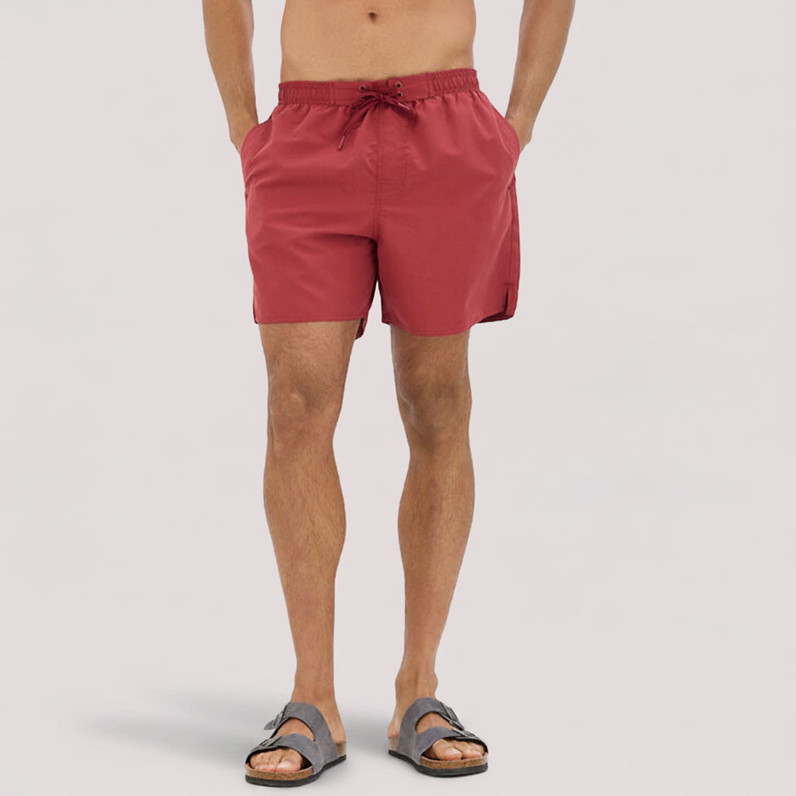 Ein Mann trägt rote Badeshorts und Sandalen.
