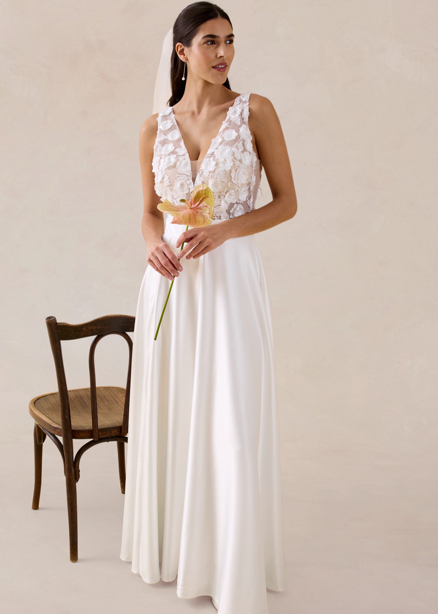 Elegantes weißes Maxikleid mit Spitzenoberteil, tiefem V-Ausschnitt und fließendem Rock. Perfekt für Sommerhochzeiten.