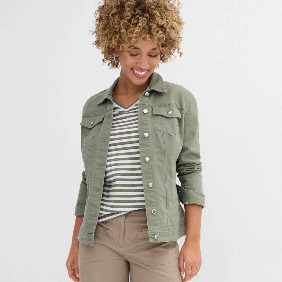 Kombination aus olivgrüner Jeansjacke, gestreiftem Shirt und beiger Hose.