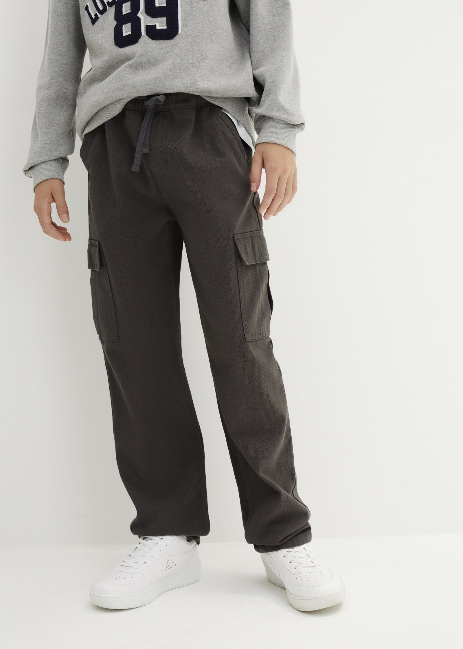 Grauer Pullover und dunkle Jogginghose.