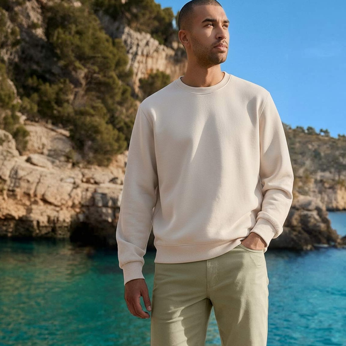 Cremefarbenes Sweatshirt und helle Hose am Meer.