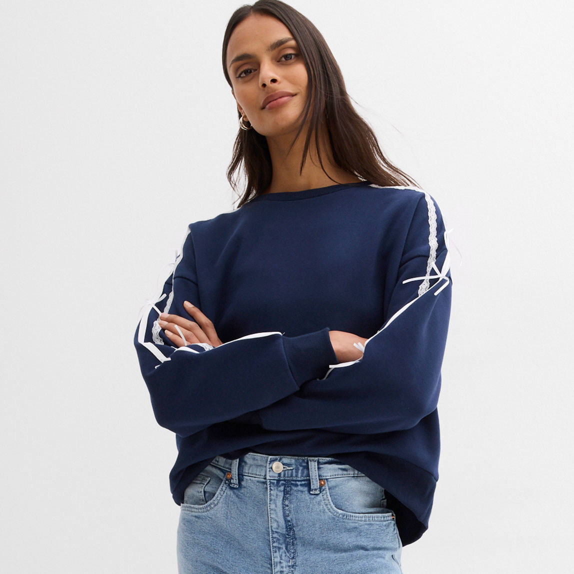Blaues Sweatshirt mit weißen Streifen an den Ärmeln. Dazu eine klassische Jeans.