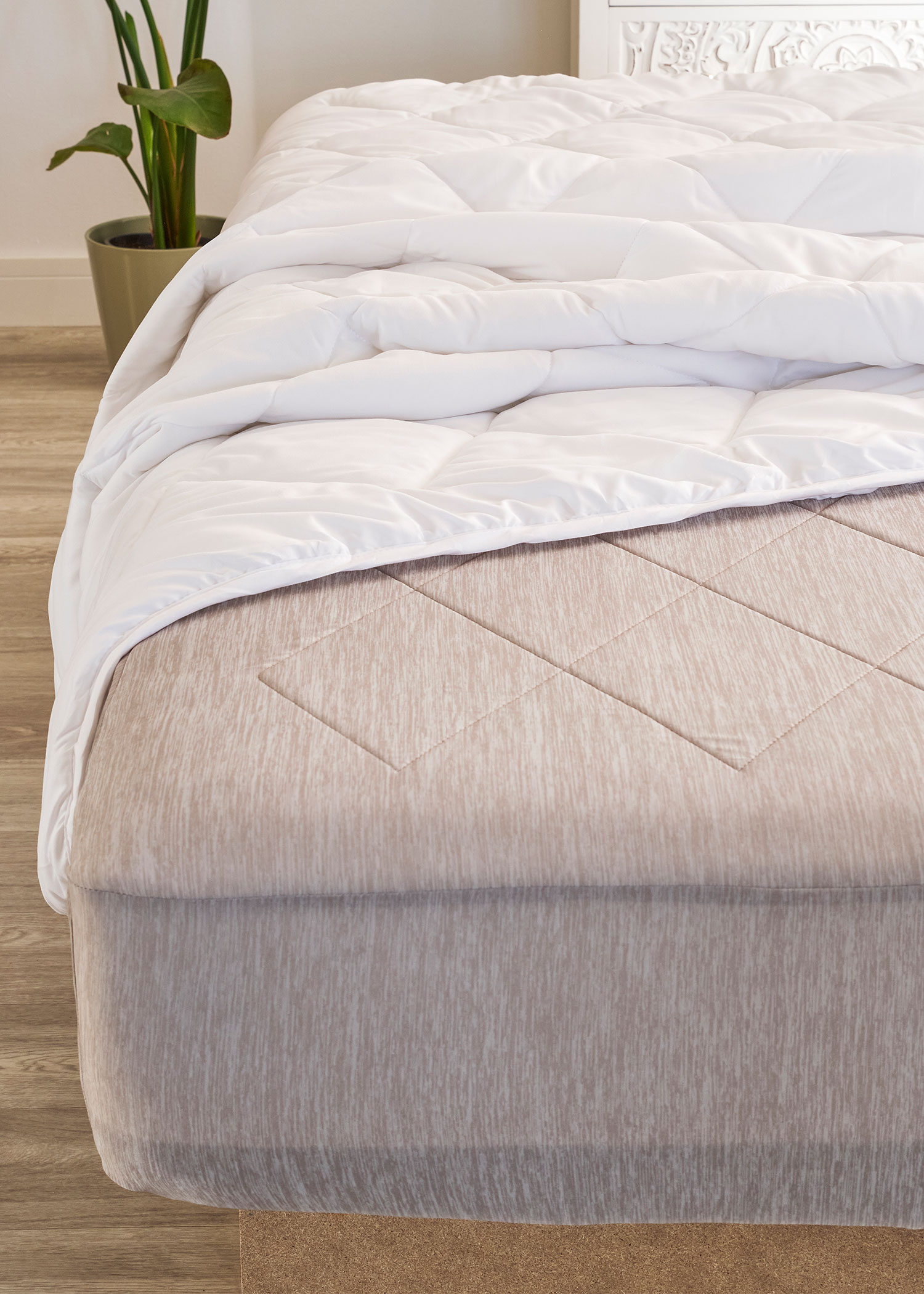 Gesteppte Decke und das gemusterte Laken auf dem Bett.