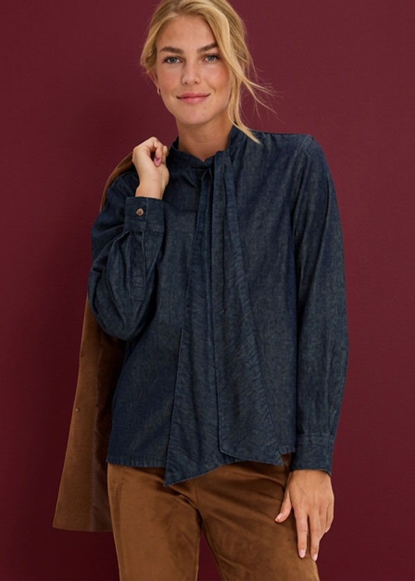 Stilvolle dunkelblaue Bluse mit Schluppe, kombiniert mit brauner Hose und Sakko.