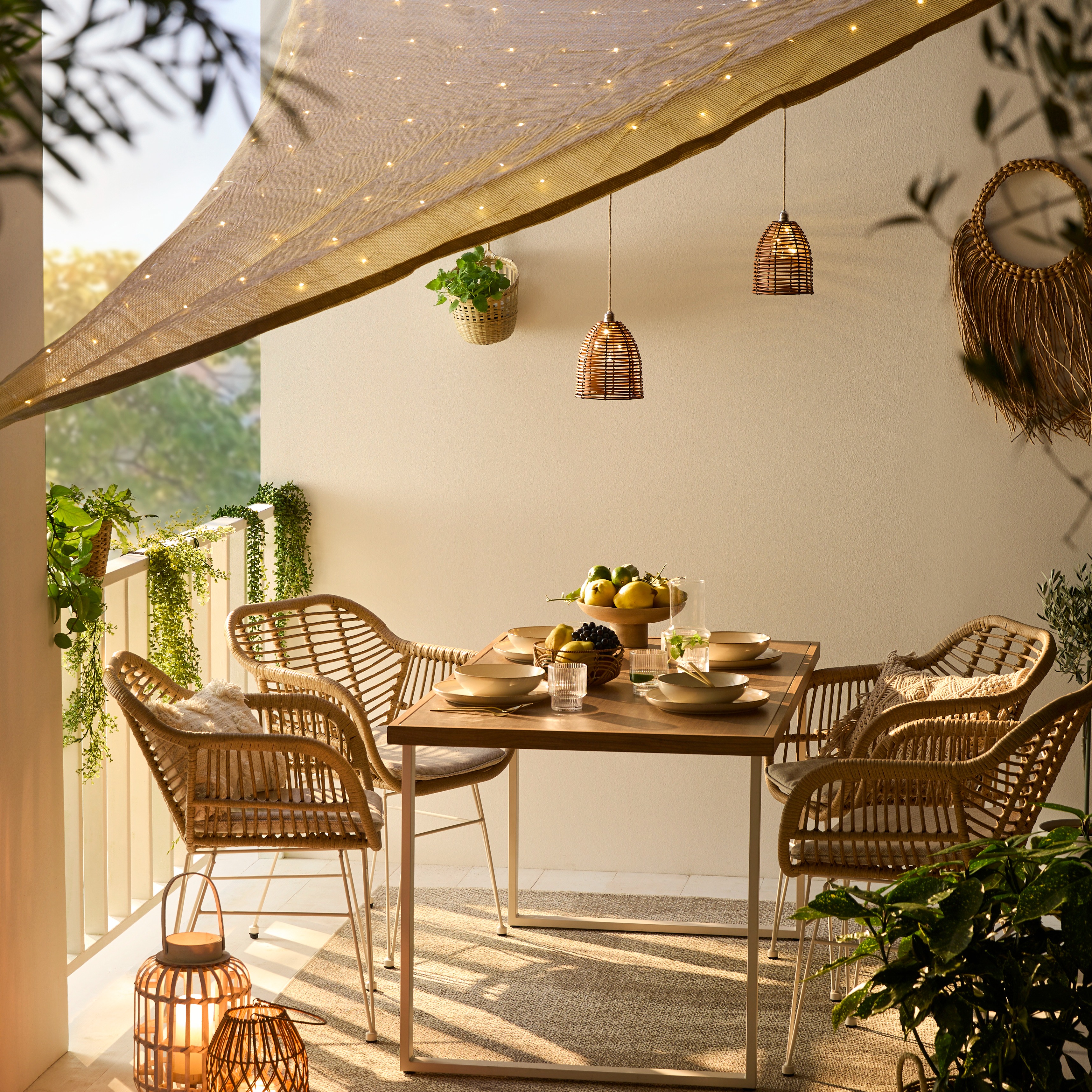 Gemütliche Terrasse mit Rattanstühlen und Holztisch, dekoriert mit Lichterketten und stimmungsvollen Laternen.