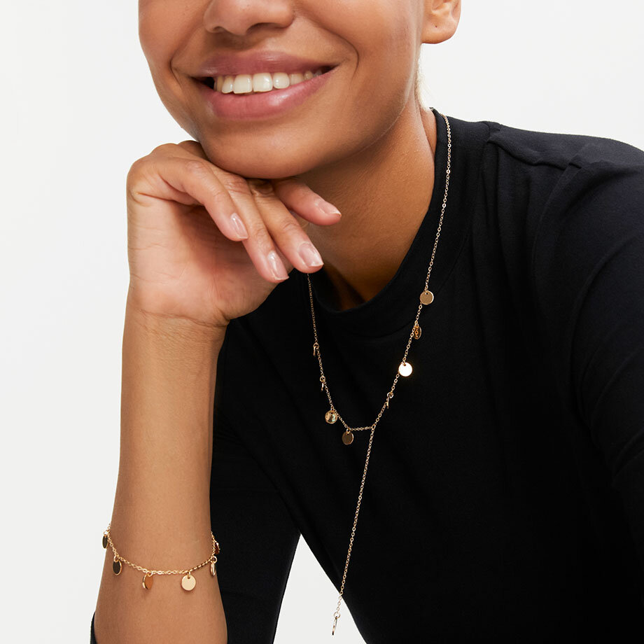 Schicke goldene Halskette und Armband kontrastieren elegant mit dem schwarzen Oberteil.