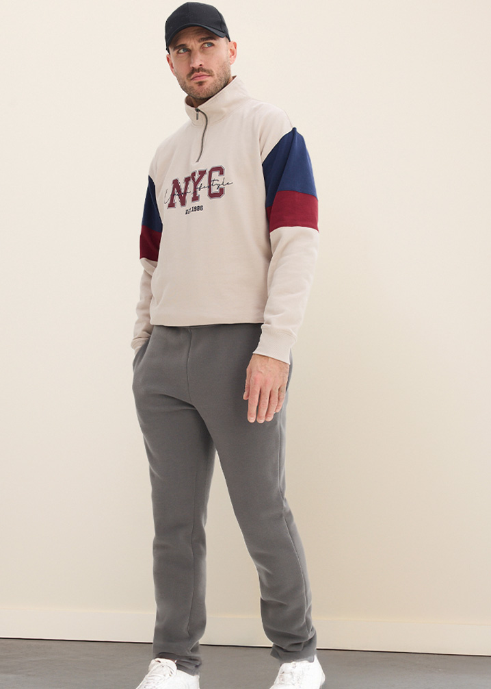 Beiges Sweatshirt mit Aufdruck und grauer Thermo-Hose.