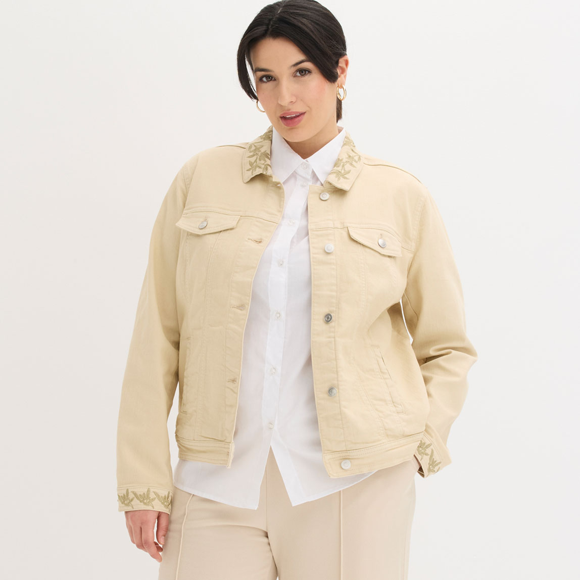 Beige Twill-Jacke mit Stickerei über weißer Bluse.