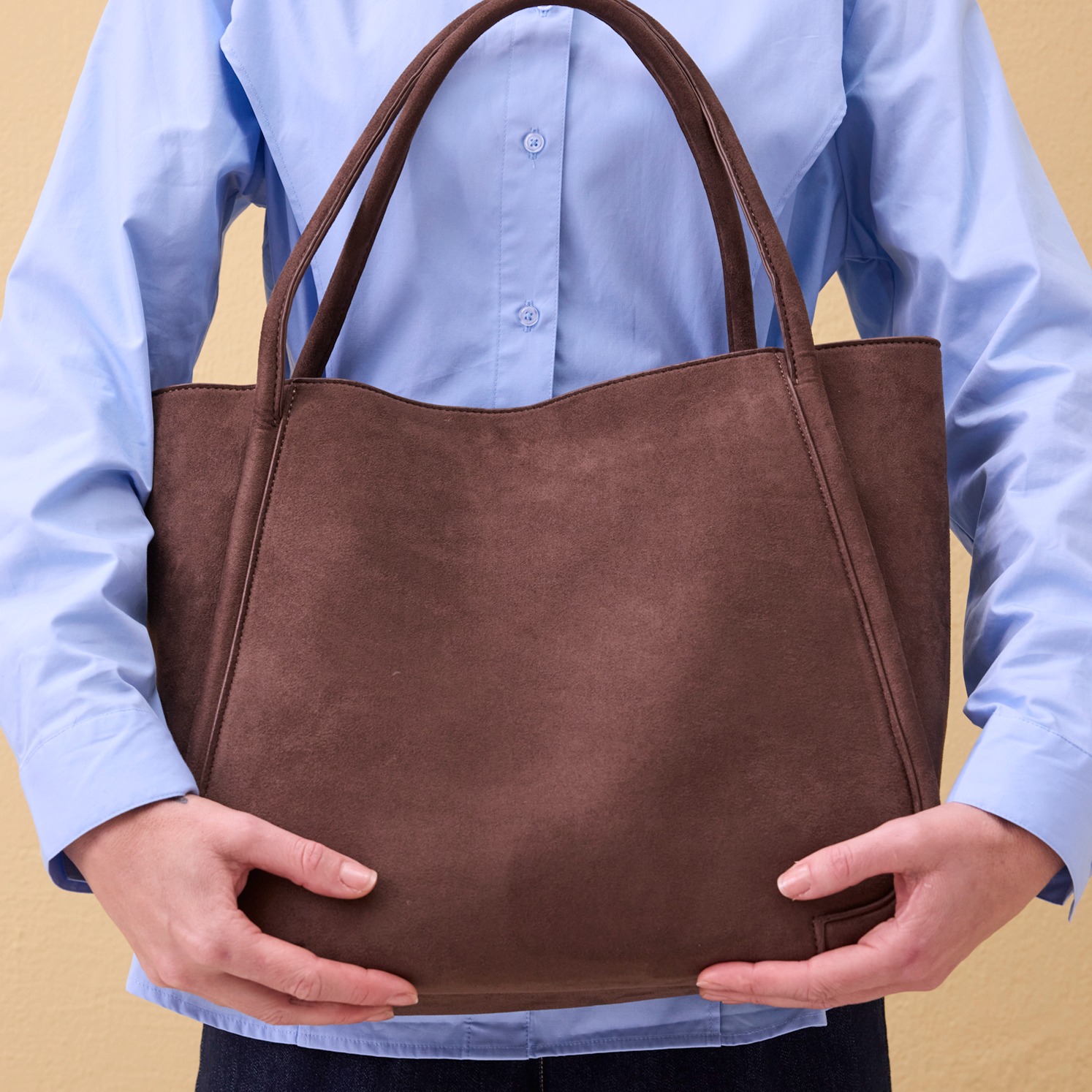 Hellblaue Bluse und braune Ledertasche.