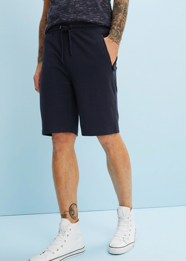 Lässige dunkelblaue Shorts, ein gemustertes T-Shirt und weiße High-Top-Sneaker.