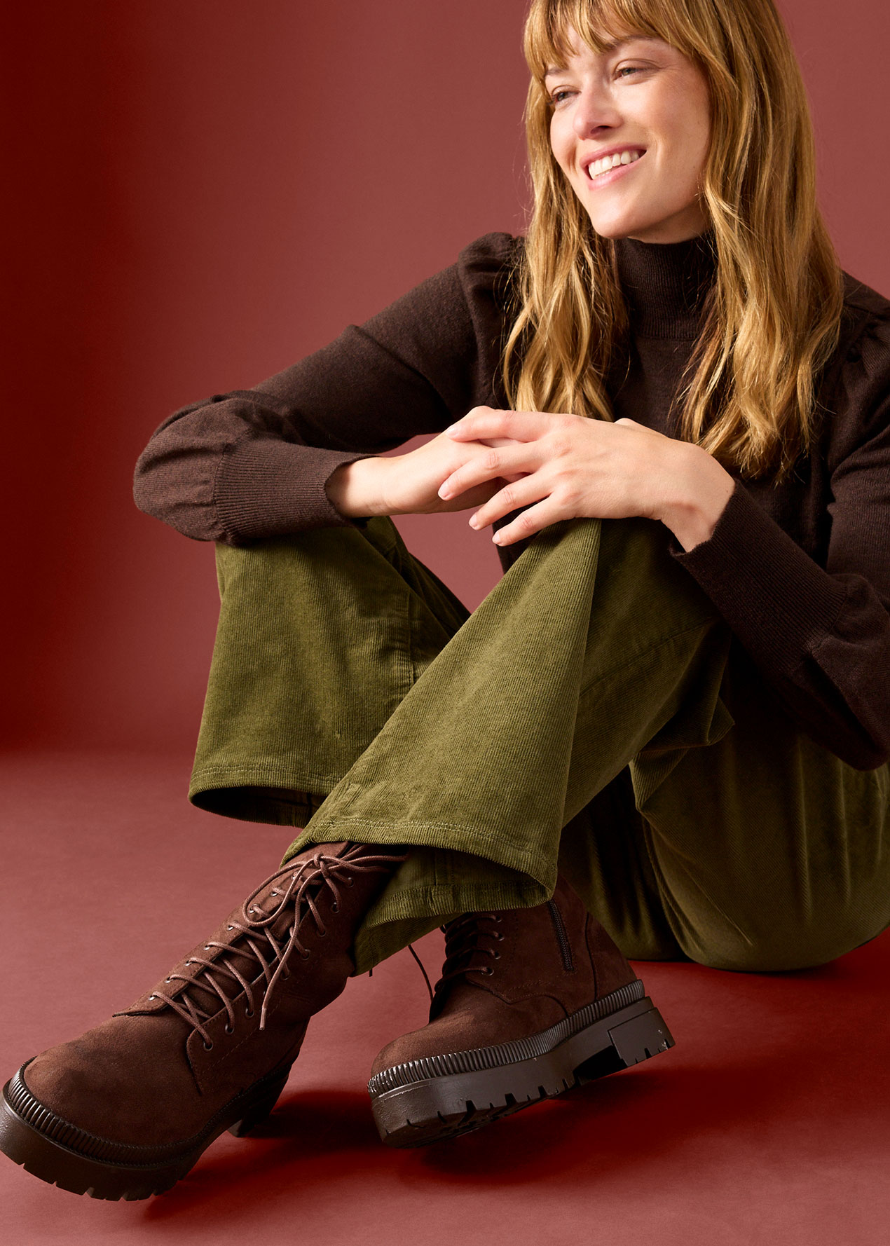 Dunkler Rollkragenpullover, bequeme olivgrüne Cordhose und stylische braune Schnürstiefel mit dicker Sohle.