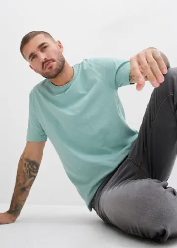 Lässiges Outfit mit weißem Grafik-T-Shirt und heller Jeans für einen entspannten Look.