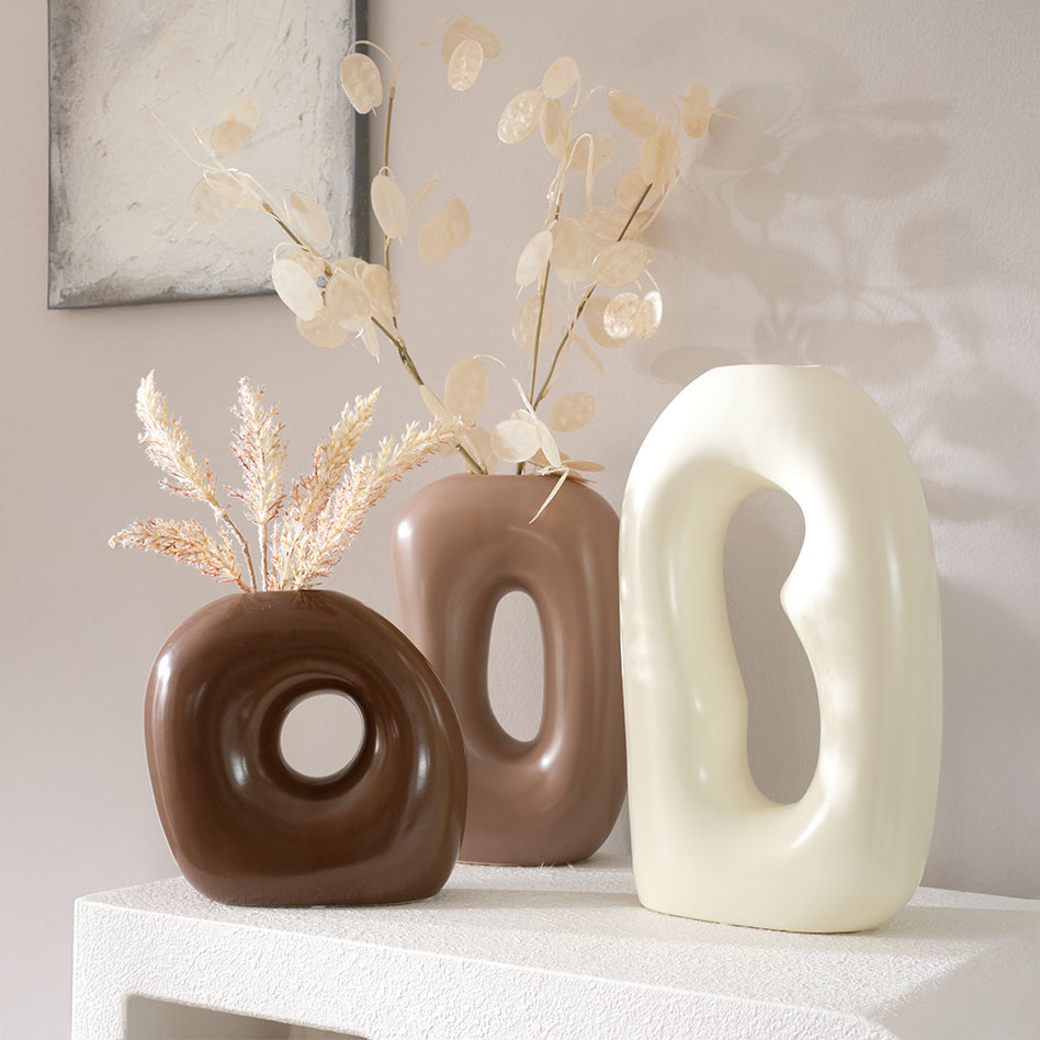 Drei kleine Vasen in braun, beige und creme mit dekorativen Trockenblümen.