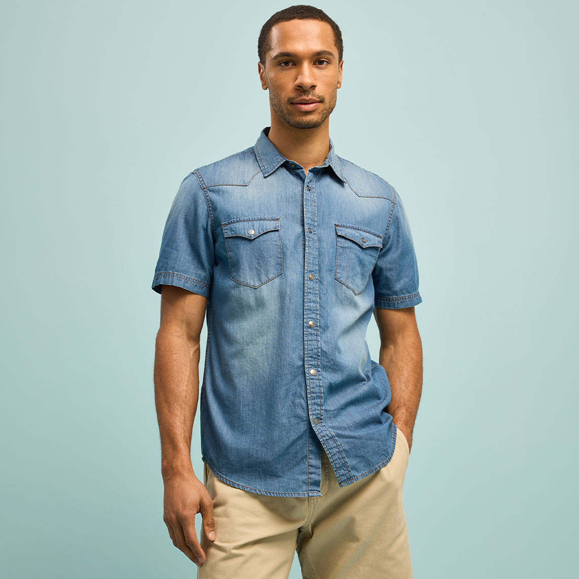 Lässiges blaues Jeanshemd mit kurzen Ärmeln und beiger Hose.