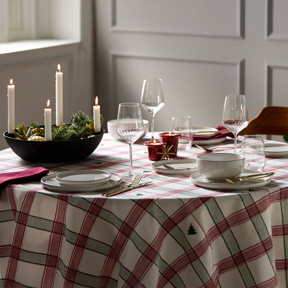 Eine karierte Tischdecke in Rot und Weiß schmückt den festlich gedeckten Esstisch.