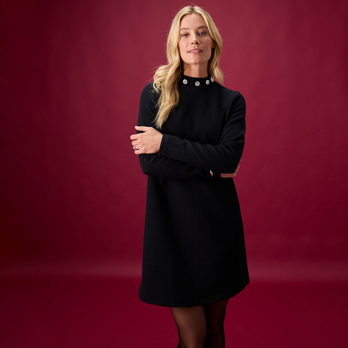 Schwarzes Kleid mit hohem Kragen und weißem Kragenschmuck. Kurze Länge und langärmelig.