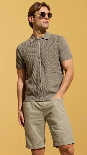 Graues gestricktes Poloshirt mit Reißverschluss und beige Shorts für einen lässigen Sommerlook.