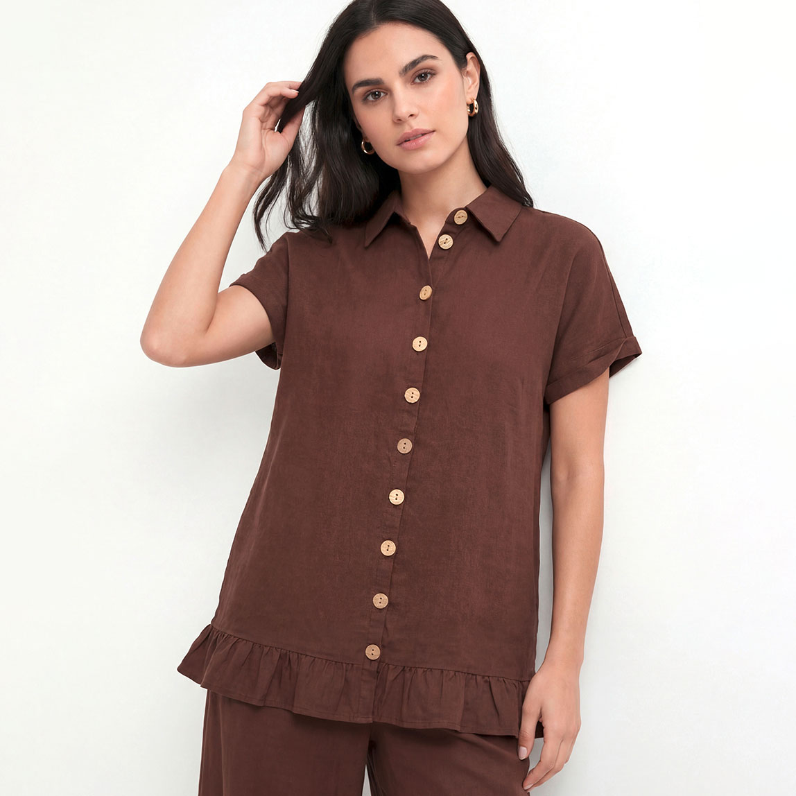 Braune Bluse mit kurzen Ärmeln und hellen Knöpfen.