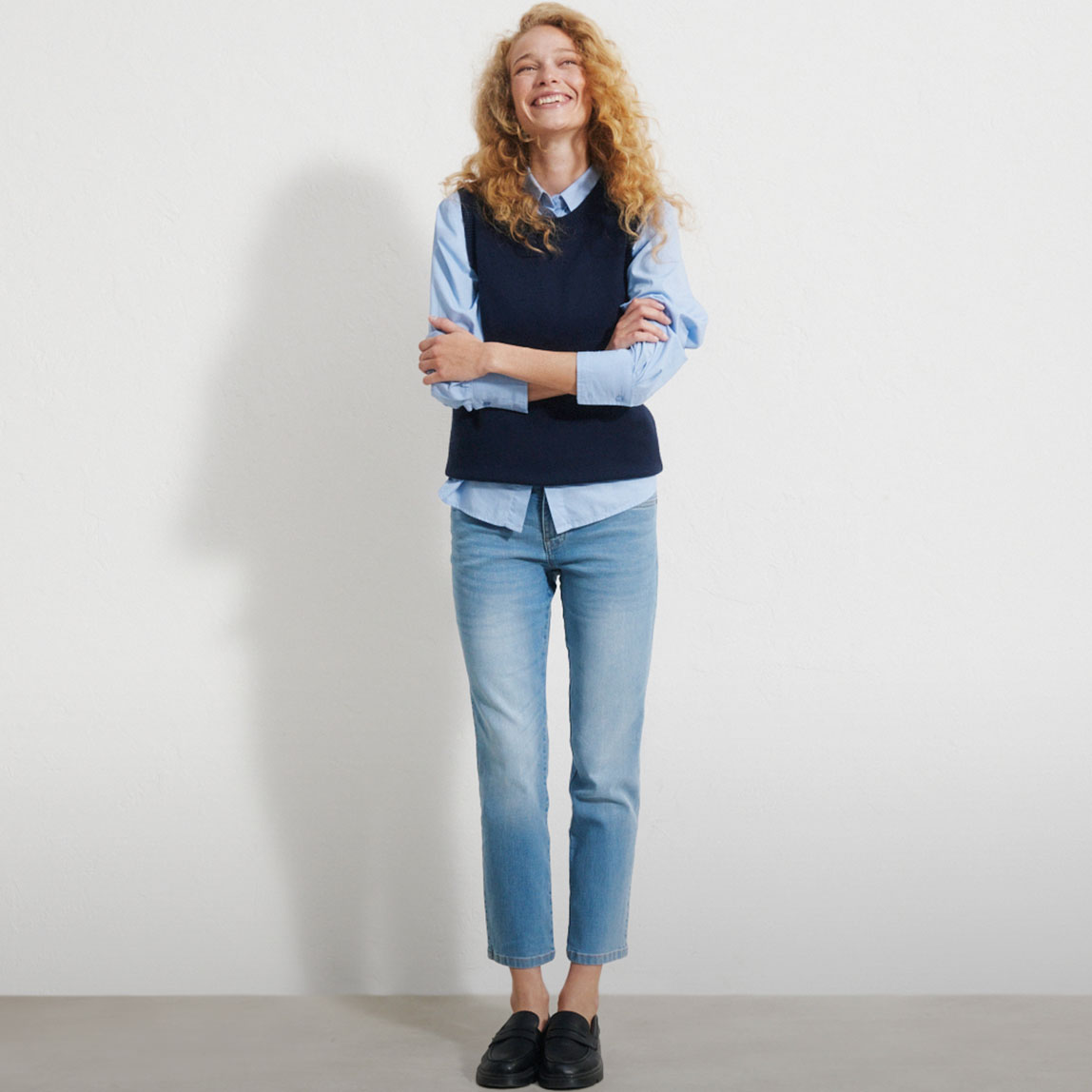 Hellblaues Hemd, dunkelblaue Weste, blaue Jeans und schwarze Loafer.