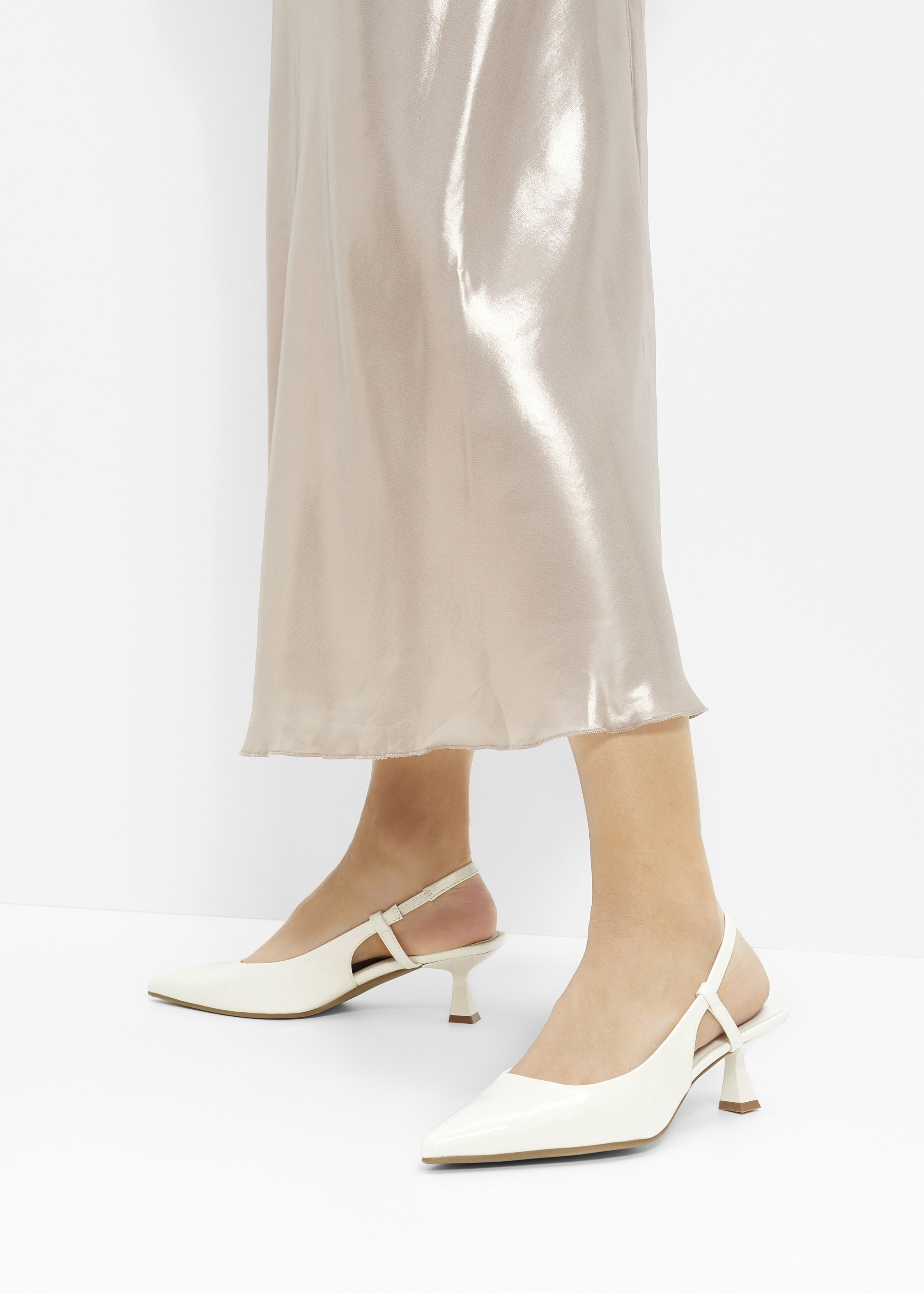 Eleganter Satin-Rock kombiniert mit stilvollen weißen Slingback-Pumps mit niedrigem Absatz.