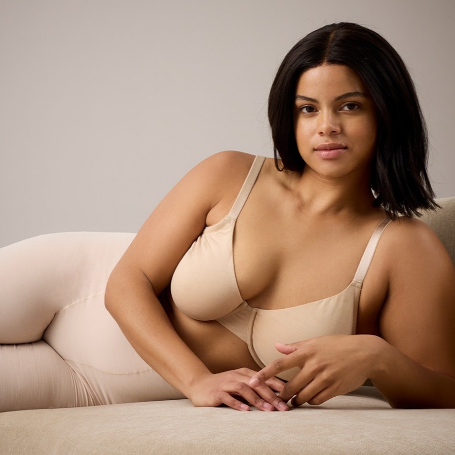 Beige Unterwäsche betont natürliche Schönheit. Elegante Silhouette auf cremefarbenem Sofa ruht entspannt.