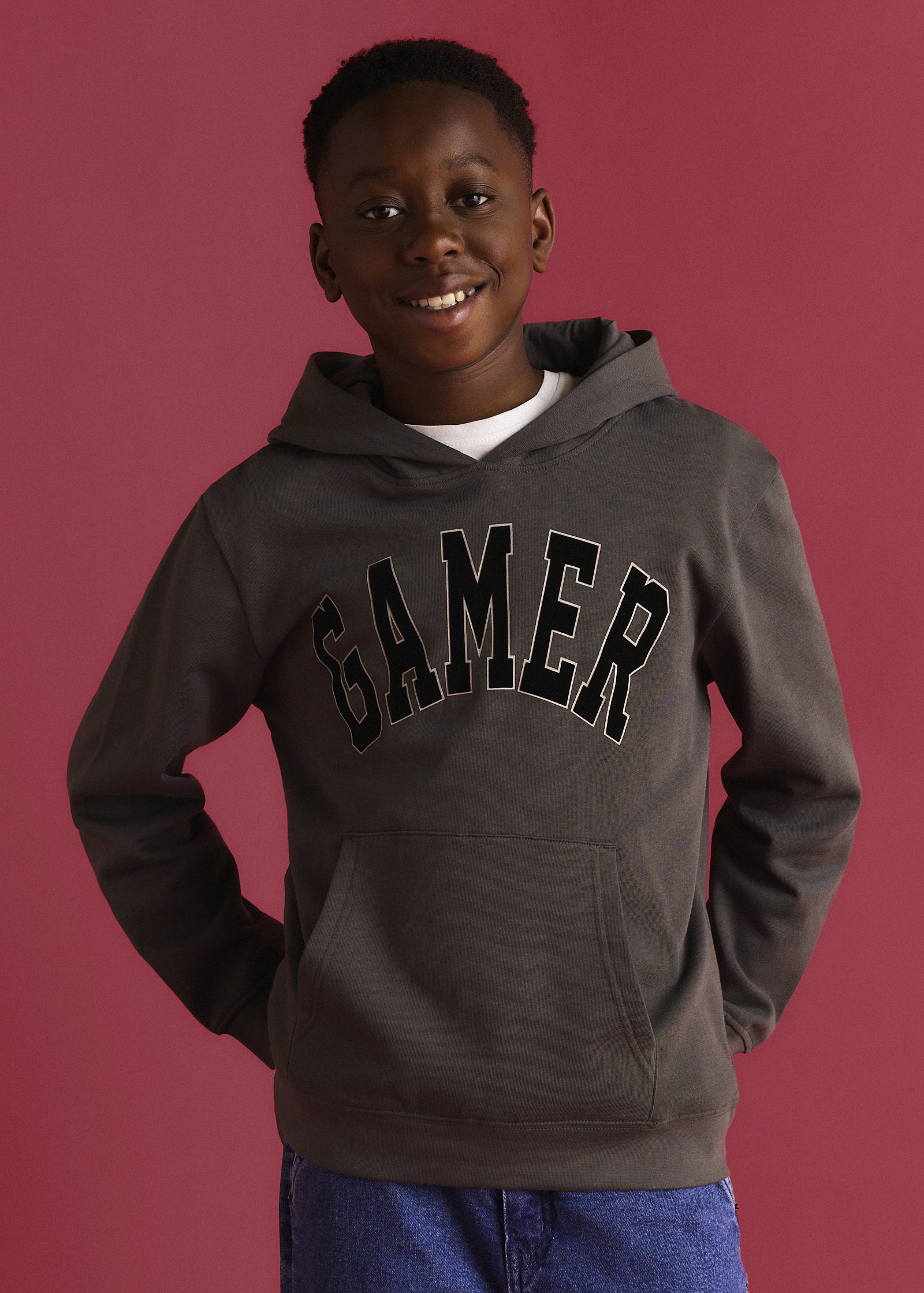 Hoodie in Grau und Schwarz mit "Gamer" Aufdruck, dazu blaue Jeans.