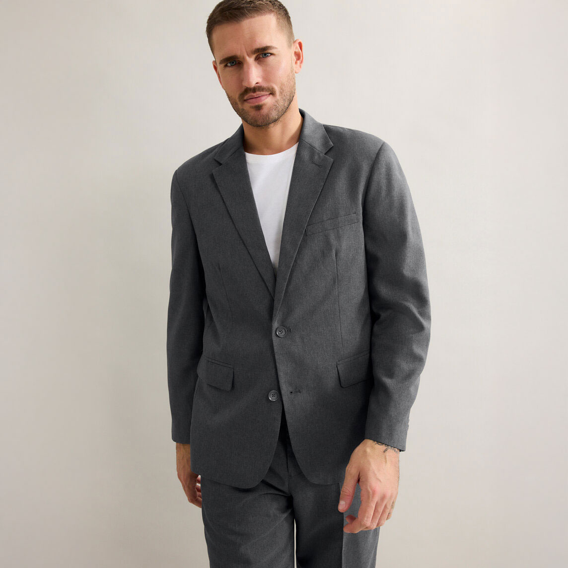 Eleganter grauer Anzug mit schlichtem weißem T-Shirt darunter. 