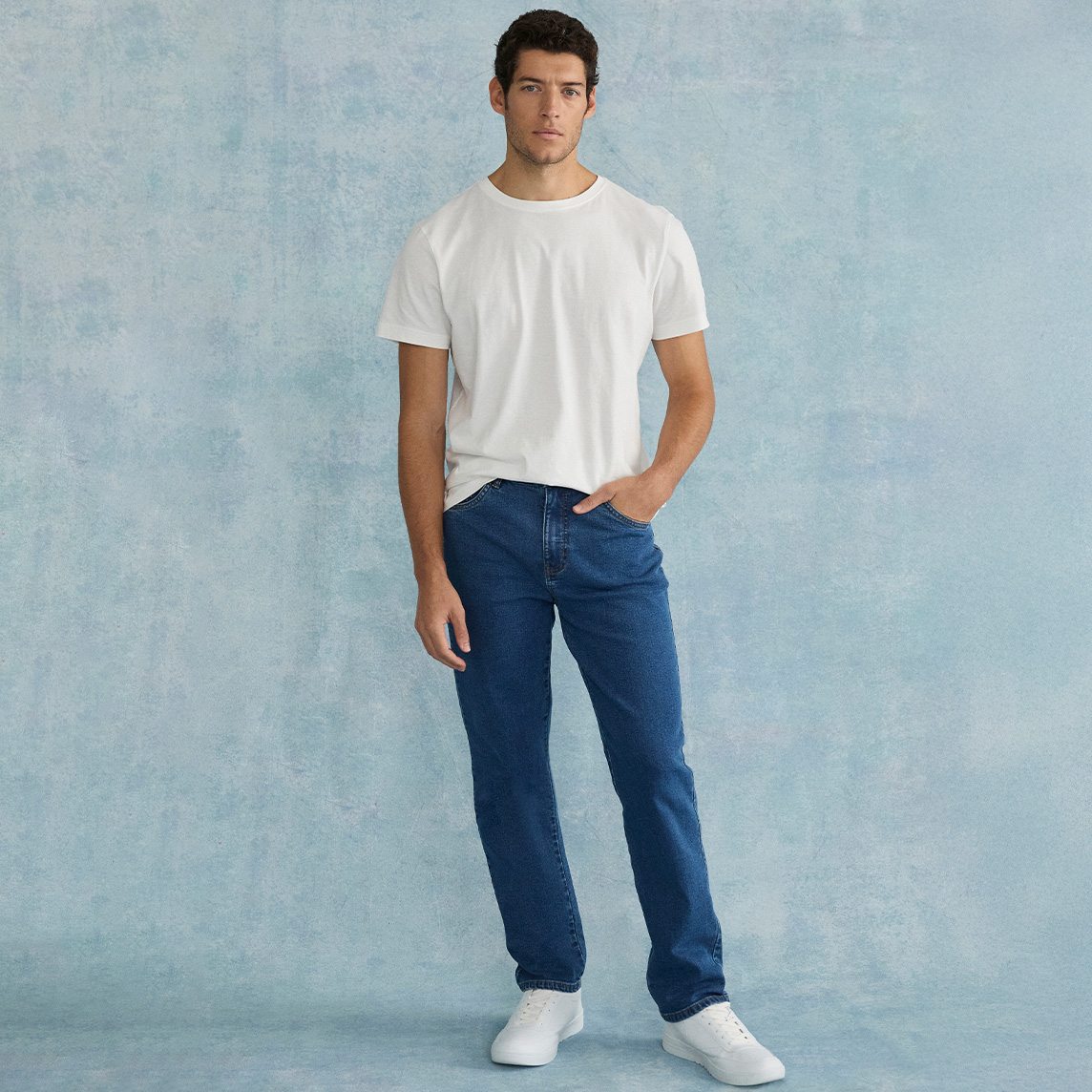 Weißes T-Shirt, blaue Classic Fit Jeans und weiße Sneakers.