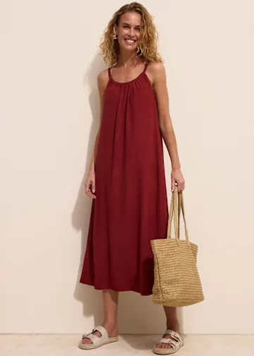 Rotes Maxikleid, bequeme Sandalen und eine Basttasche.