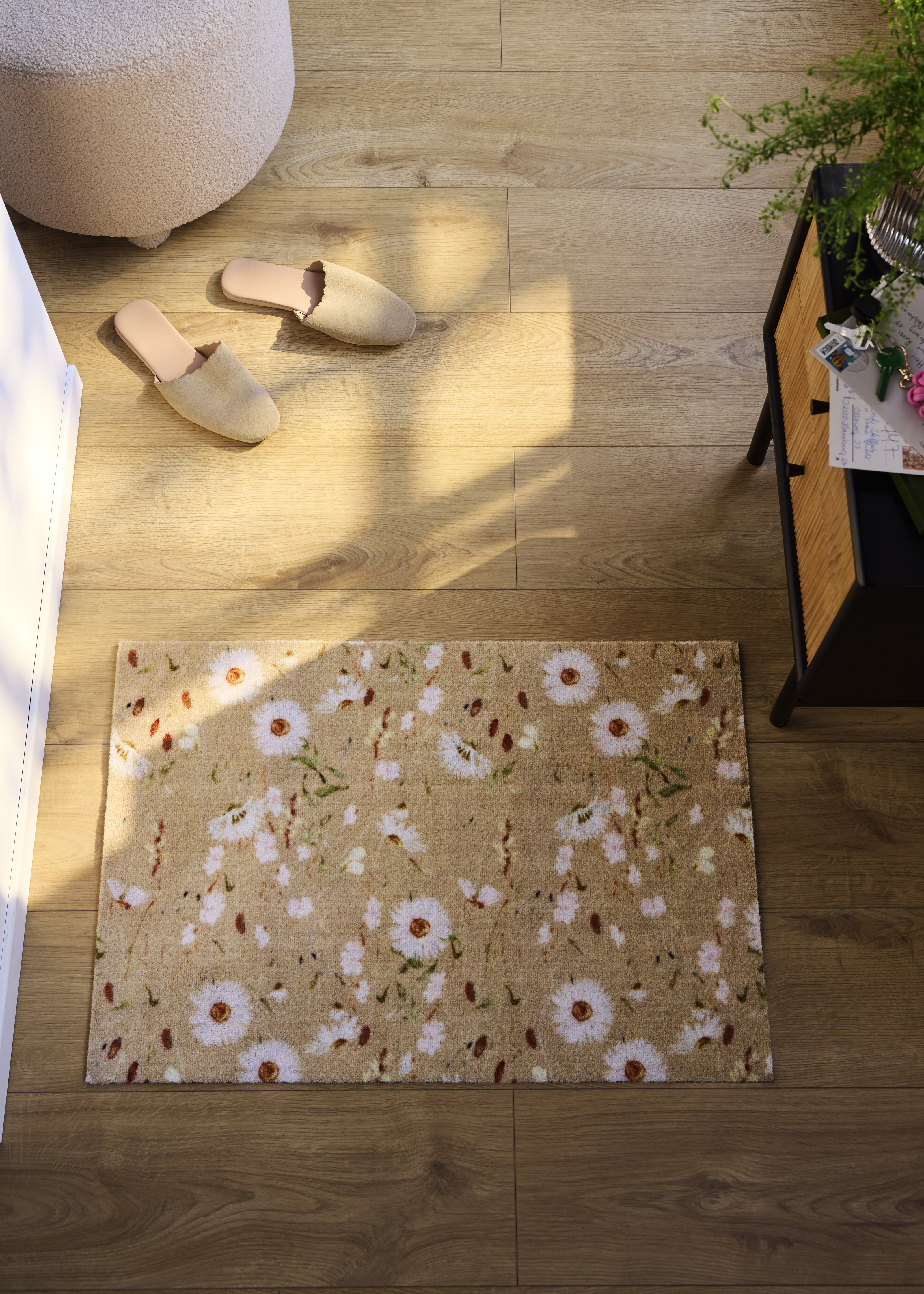 Bequeme Hausschuhe auf Holzboden neben floraler Fußmatte.
