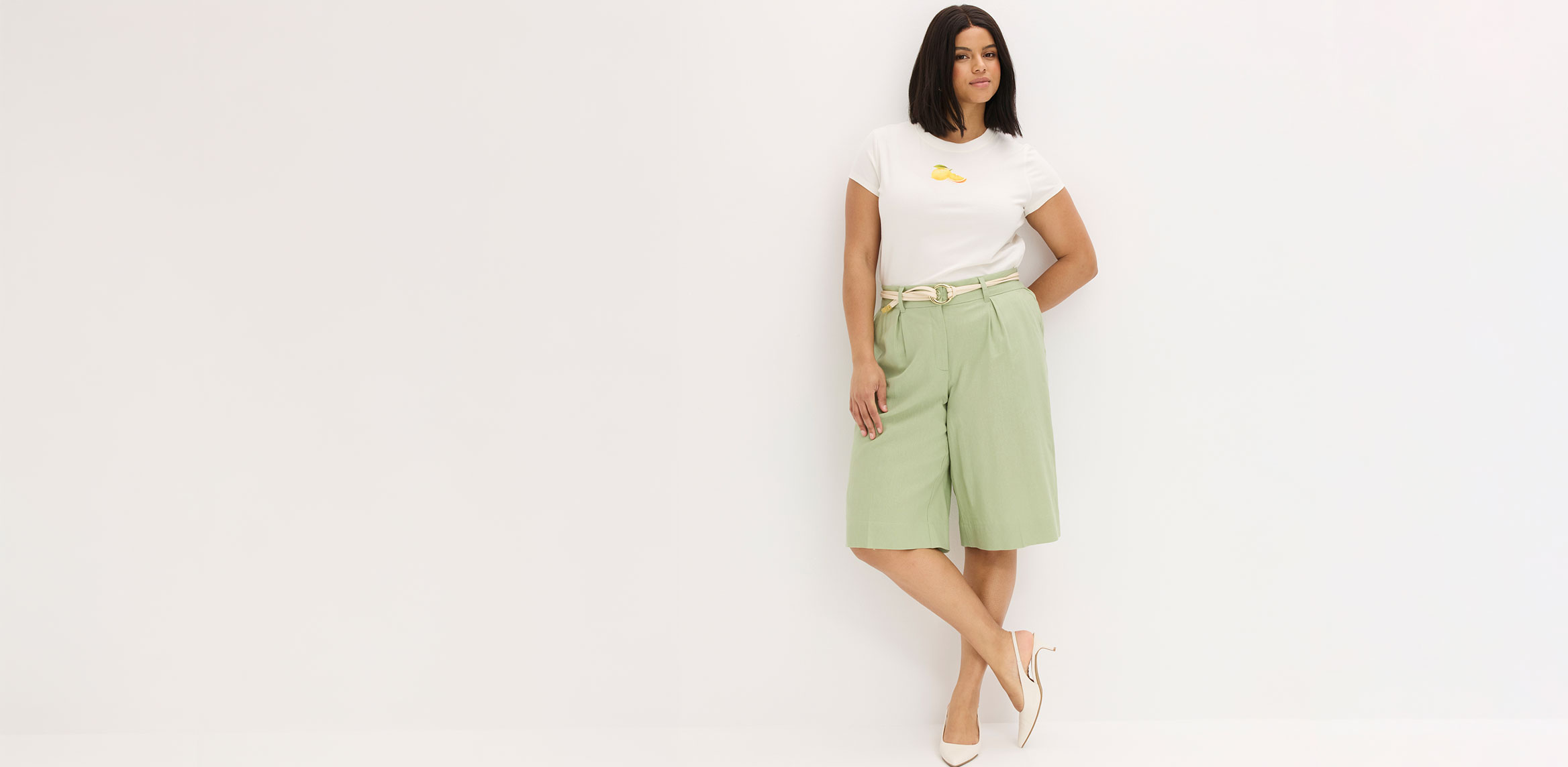 Weißes T-Shirt, mintgrüne Bermuda-Shorts und beige Sandalen.