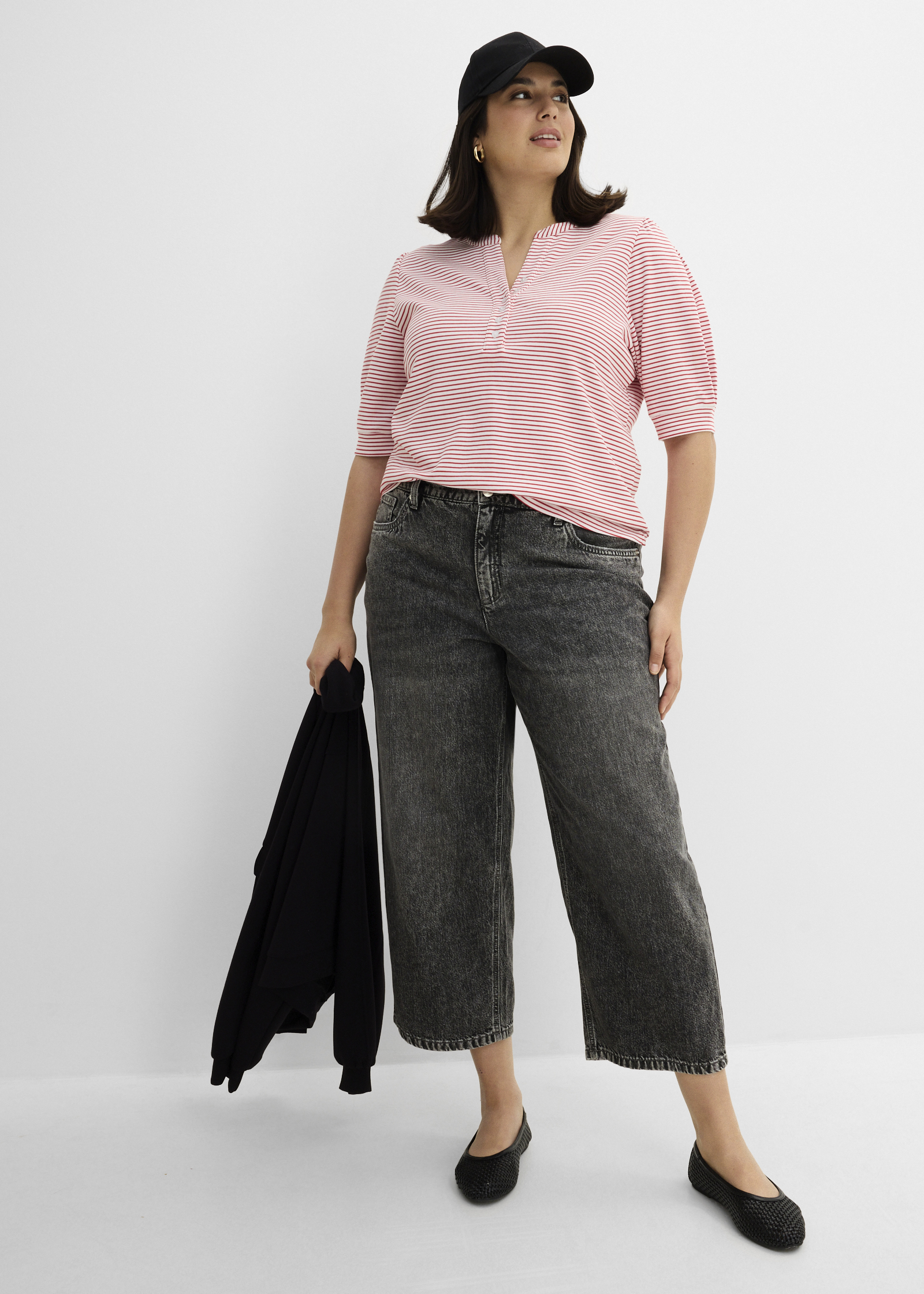Gestreiftes Oberteil, weite Acid-Wash-Jeans, schwarze Mütze und Ballerinas sind zu sehen.