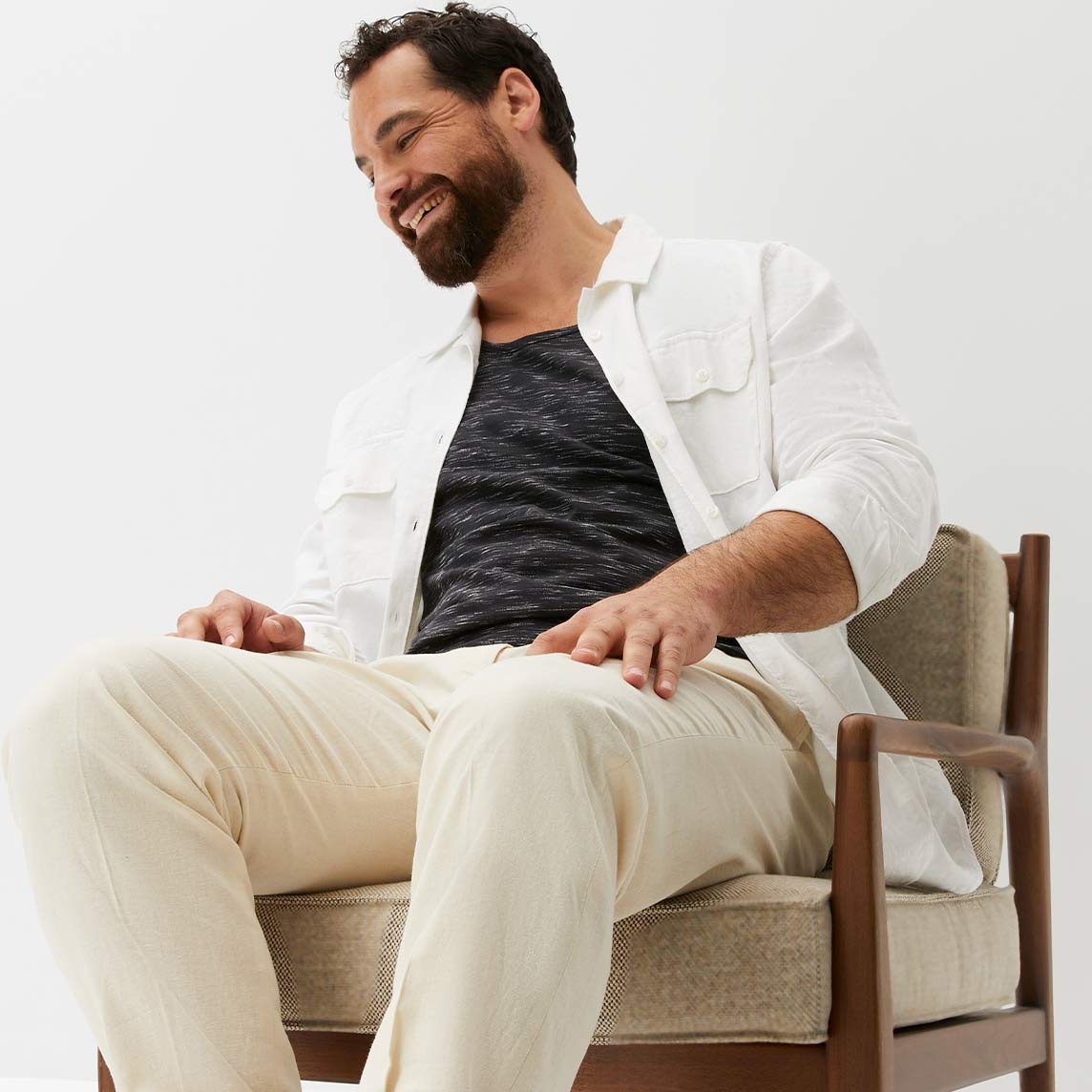 Outfit aus weißem Hemd, dunklem T-Shirt und heller Hose.