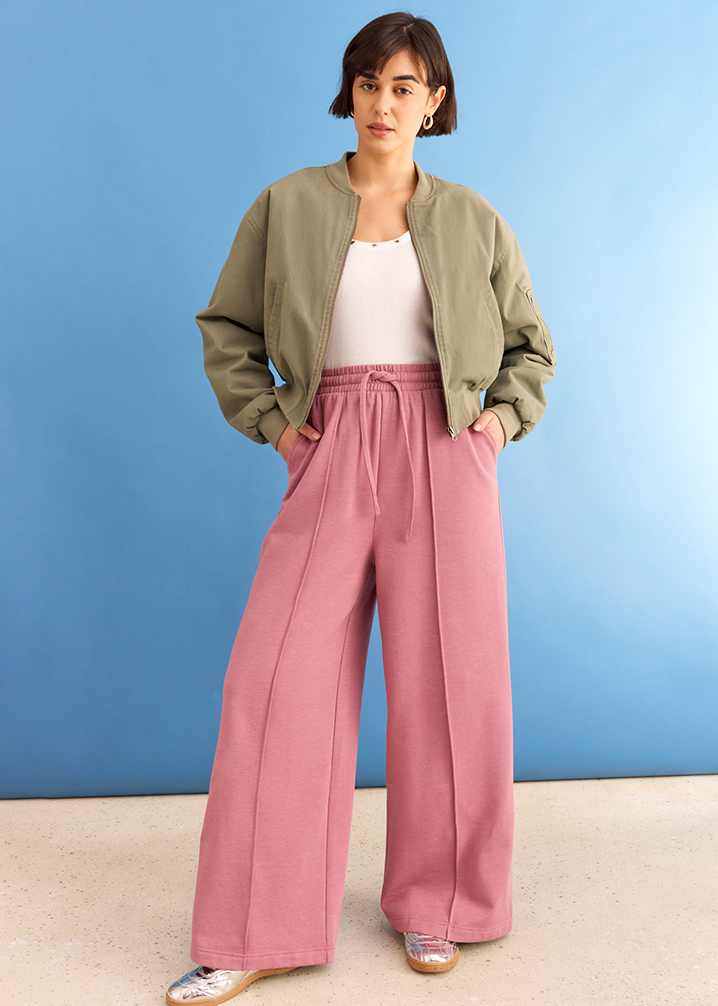 Olivgrüne Bomberjacke, weißes Top und rosa Palazzo-Hose ergeben einen lässigen, farbenfrohen Look.