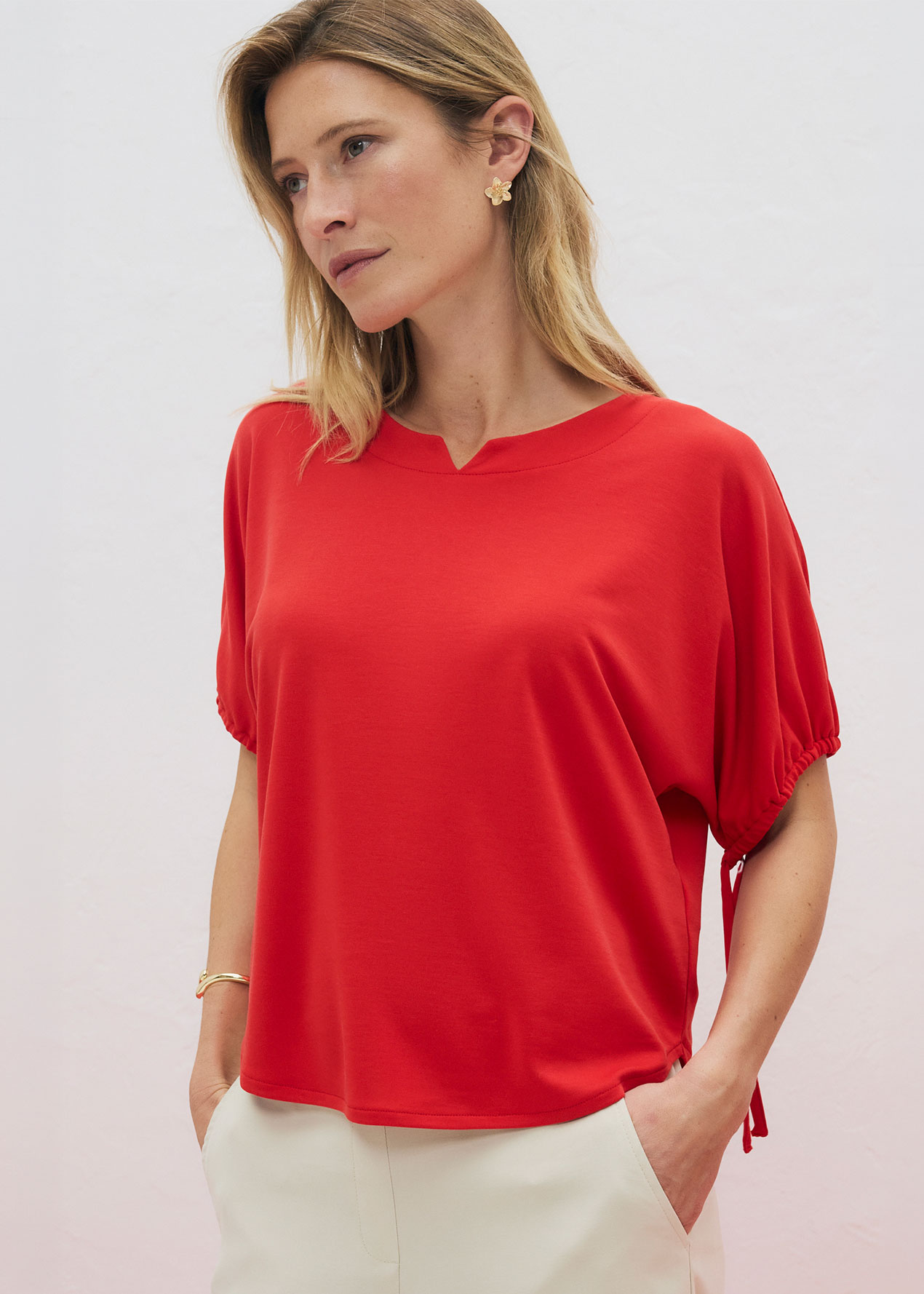 Elegantes rotes Oberteil mit weiten Ärmeln und V-Ausschnitt, kombiniert mit heller Hose.