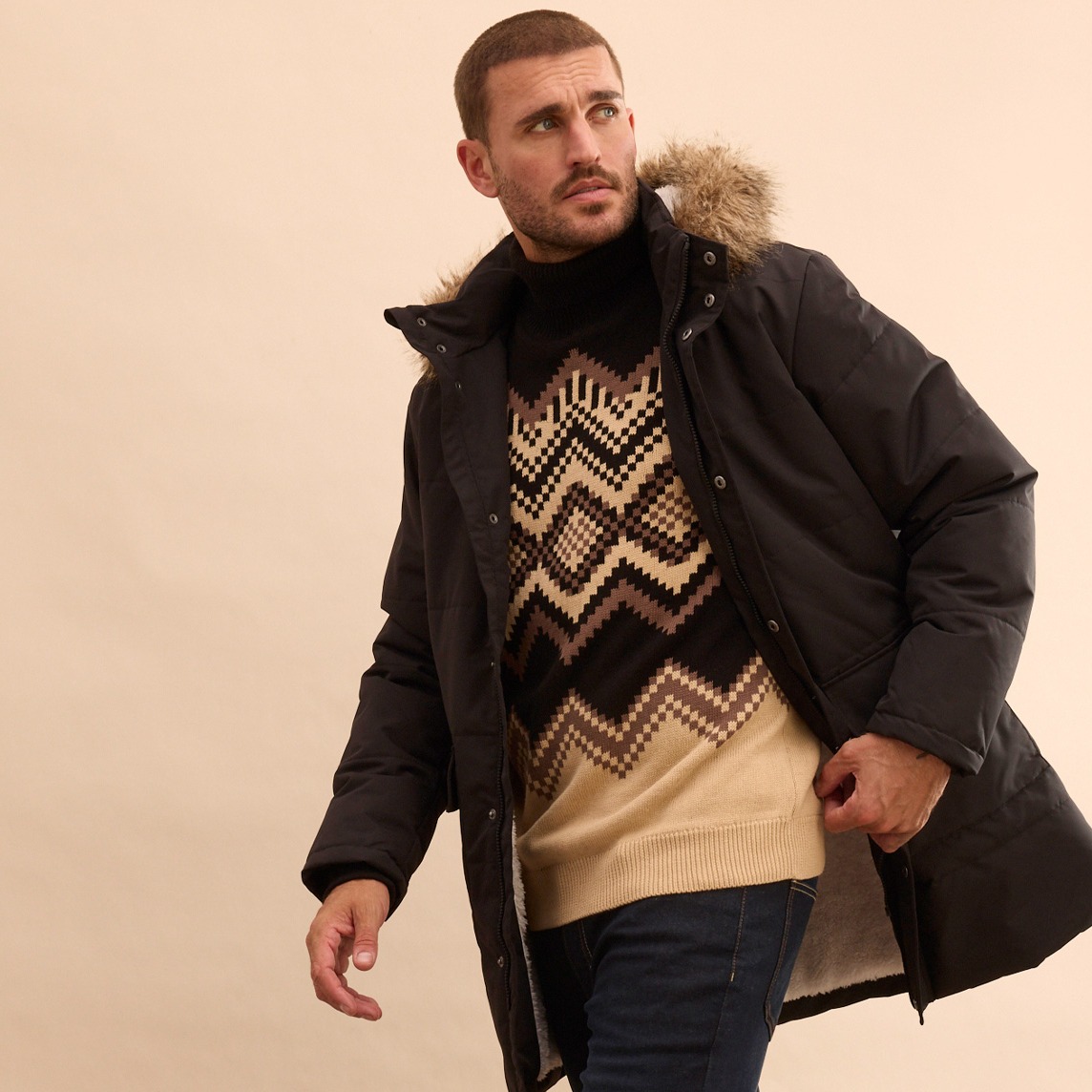 Stilvoller Look mit schwarzer Winterjacke, gemustertem Pullover und Jeans für kühle Tage.