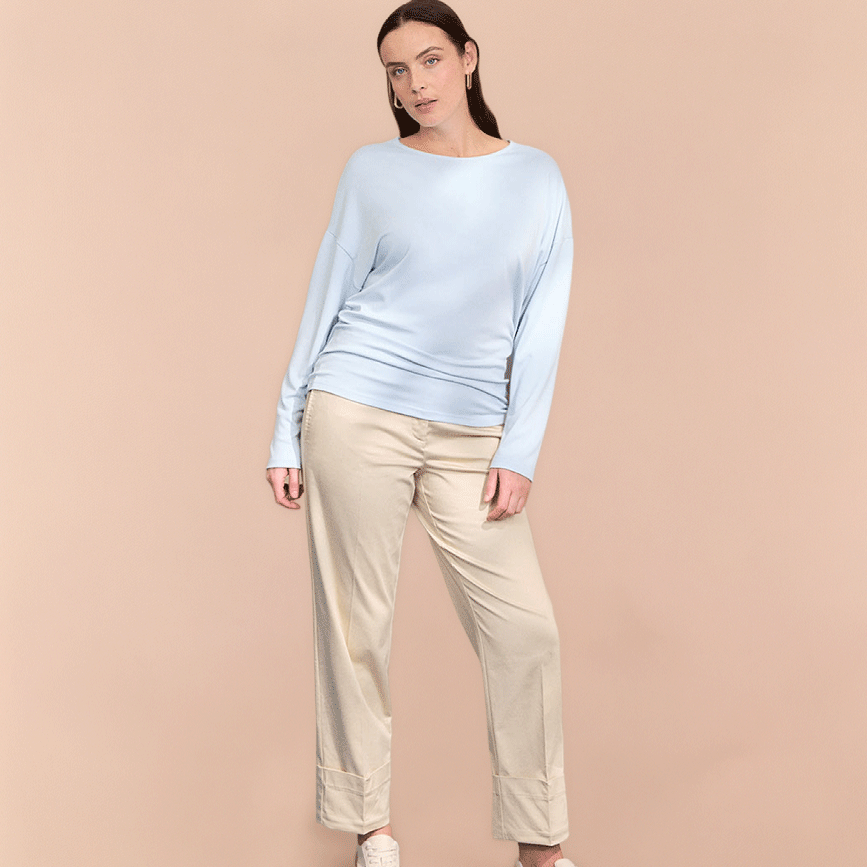 Leichter hellblauer Pullover und beige Hose.